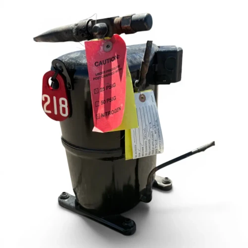 Front-right view of a used Copeland CRA1-0150PFV 1.5 HP compressor (1 phase 208-230 volt), a black hermetic compressor with a bent copper discharge line, a red inventory tag "8," and yellow/red caution tags reading "NITROGEN" hanging from the top valve.