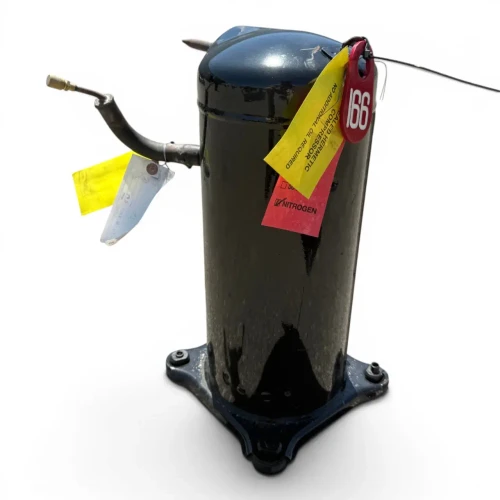 Closer front-angled view of the used Copeland ZR61K3E-PFV 5 HP compressor, 1 phase 208-230 volt, focused on the top and copper lines with the brass fitting and red/yellow paper tags, the black terminal box with red and yellow wires on the left side, and the cast mounting base with bolted feet visible below.