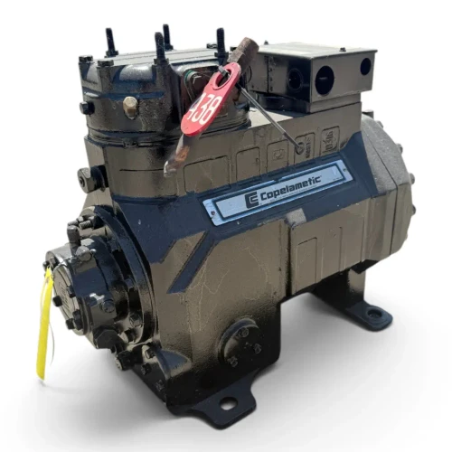 Front-right view of a used Copeland 2DA3-F23KE-TFC 6 HP reciprocating compressor, 3 phase 208-230 volt, showing the "Copelametic" nameplate, a red oval "438" tag, and a yellow inventory tag hanging from the crankcase.