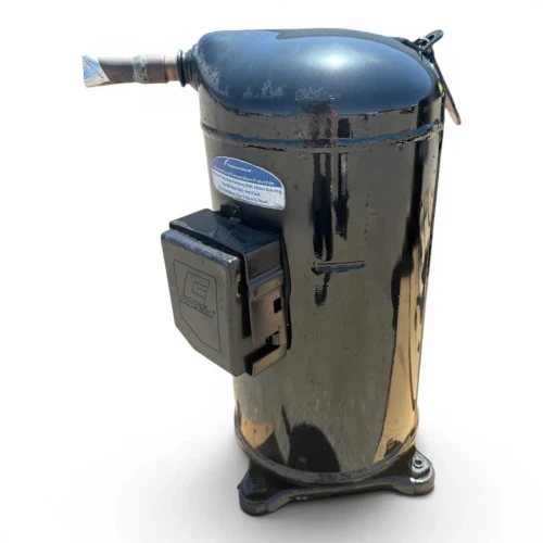 Front-left angled view of a used Copeland ZB50KCE-TF5 6.5 HP compressor, 3 phase 208-230 volt, showing a worn brass-toned black cylindrical body with a red round tag numbered "390" at the top, a black terminal box on the left side, and the cast mounting base with bolted feet below.
