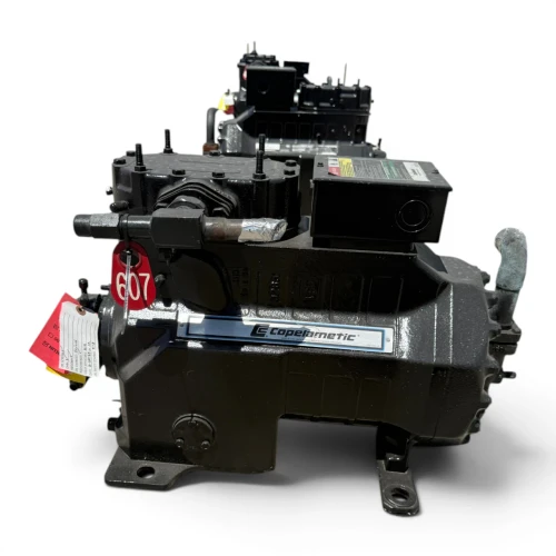 Three-quarter front-right view of a used Copeland 3DA3-R10ME-TFC 7.5 HP compressor, 3 phase 208-230 volt, with a dark gray-olive housing, blue Copelametic nameplate, and a red round inventory tag hanging from the top oil-fill valve alongside a yellow "add oil" tag.