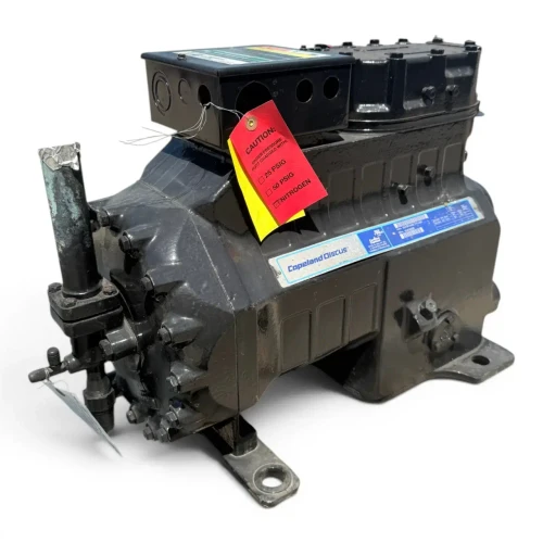 Straight-on front view of the used Copeland 3DF3-R15ME-TFC 12 HP compressor, showing the blue "Copeland Discus" nameplate with model and serial data, a thin wire probe protruding from the top, and the same red-and-yellow caution tag on the terminal box.