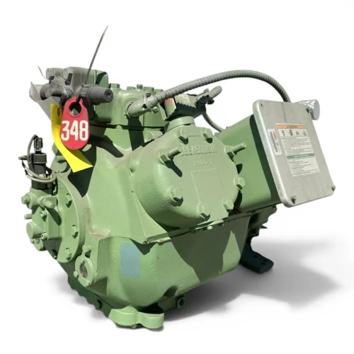 Angled front-right close-up of the used Carlyle 06EY775-34ARP 20 HP compressor, 3 phase Dual Voltage, showing the hex-bolted cylinder head, coiled wiring conduit, and a foil-wrapped service valve fitting on the left side.