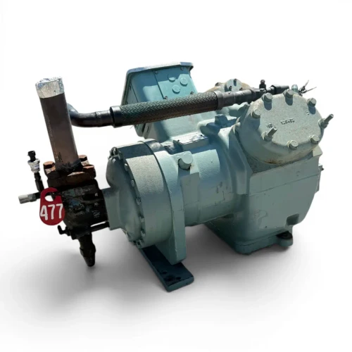 Front view of the used Carlyle 06EY766-34ARP 20 HP compressor, 3 phase 460 volt, showing the stamped cylinder head marking "WS 120002", the red "477" round inventory tag, and the braided hose and foil-capped pipe on the left side.