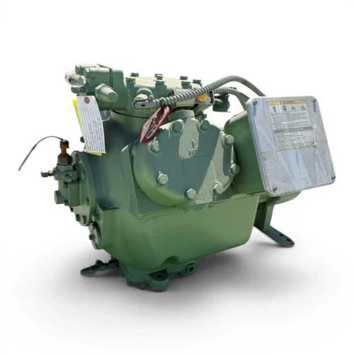 Front view of the used Carlyle 06EA565300 25 HP compressor, 3 phase Dual Voltage, showing the silver Warning and Safety Instructions label box centered on the terminal compartment, a yellow tag on the left valve, and the stamped model number on the cylinder head.