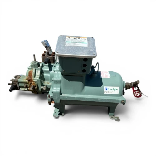Front-right three-quarter view of the used Carlyle 06TR065F2EA 35 HP compressor (3 phase Dual Voltage), teal-green shell with a Carlyle logo sticker, a red round tag numbered "456" near the valve, a rust-toned copper elbow fitting with a foil-wrapped cap, and two additional compressor units visible out of focus in the background.