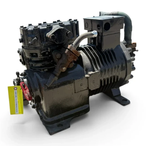 Straight-on front view of the used Copeland 9RS2-076A-TFC 7.5 HP compressor, 3 phase 208-230 volt, with the black finned housing, silver Emerson Copeland nameplate, and a yellow "add oil to compressor" tag hanging near the base.