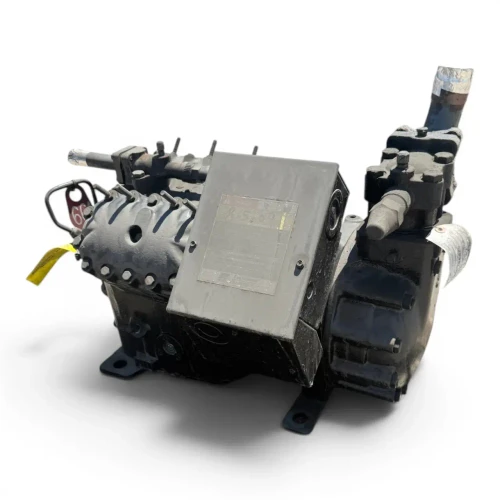 Front three-quarter view of the used Copeland 4RL1-150A-TSK 15 HP compressor (3 phase, dual voltage), black housing with a red round inventory tag and a yellow oil-service tag hanging at left, a large gray "DANGER" caution placard on the terminal box, and a foil-wrapped copper tube at upper right.