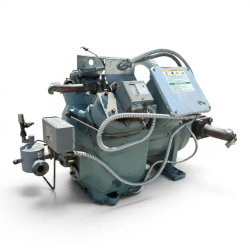 Front-right view rotated further of the used Carlyle 06ER450300 15 HP compressor - 12048 (3 phase Dual Voltage), showing the full body profile with the "MICRO-SET" gauge, WARNING terminal cover, and a rust-stained coupling flange with a foil-wrapped shaft at the right.