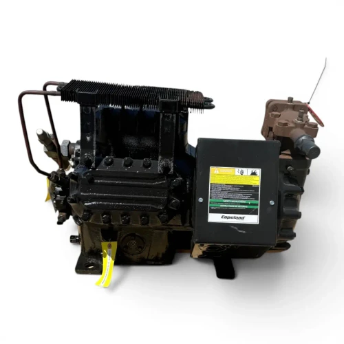 Angled front-right view of the used Copeland 6DL3-F93KE-TSK 27 HP compressor, 3 phase Dual Voltage, black finish, showing the finned oil cooler on top, a black "Copeland Danger" terminal box, and a yellow tag hanging from the base.