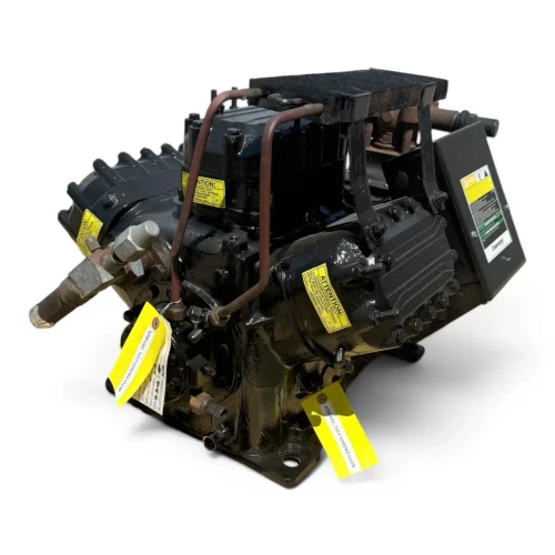 Angled front-left view of the used Copeland 6DL3-F93KE-TSK 27 HP compressor, 3 phase Dual Voltage, showing multiple yellow "Attention" and "Add Oil to Compressor" tags, the copper crankcase heater tubing, and the black terminal box with a green safety label.