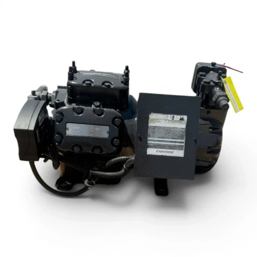 Front-right three-quarter view of the used Copeland 6DJN-F11ME-TSK 30 HP compressor - 12074 (3 phase Dual Voltage), showing two yellow "ATTENTION" caution labels on the cylinder head and valve body, a "CoreSense Protection" control module mounted at the right, and a foil-wrapped shaft stub.