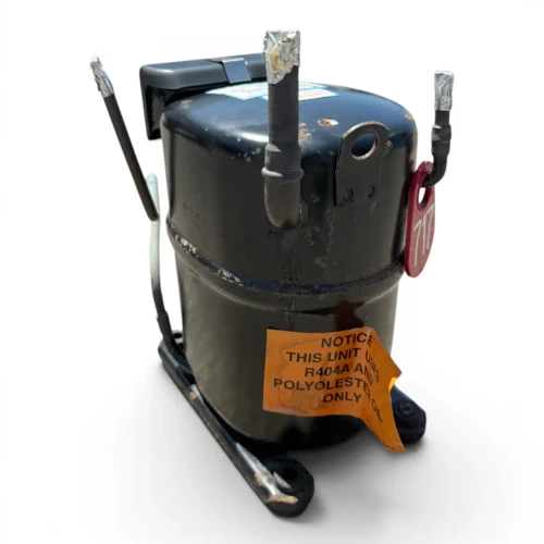 Rear-right view of the used Copeland RS70C1E-TFC 1 HP compressor - 11833, showing a bilingual electric-shock warning label on the lower shell, the black terminal box on the right, foil-wrapped tubes, and a red service valve cap at upper left.