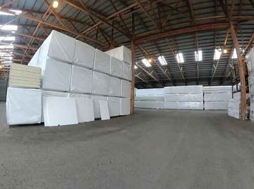 Stacked pallets of insulated cold storage panels wrapped in plastic, showing construction