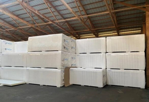 Stacked pallets of insulated cold storage panels wrapped in plastic, showing construction