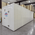 White walk-in cooler unit with closed hinged door, featuring insulated panel walls front right view