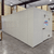White walk-in cooler unit with closed hinged door, featuring insulated panel walls front left view