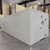 White walk-in cooler unit with open hinged door, featuring insulated panel walls