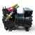 Front-angled view of the used Copeland KARA-010E-TAC 1 HP compressor (mirrored/reversed orientation), showing the yellow "ADD OIL TO COMPRESSOR" tag and a partially visible red tag near the top service valves, with the terminal box on the left.