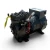 Opposite-side view of the used Copeland KALA-015E-TAC 1.5 HP compressor, 3 phase 208-230 volt, showing the bare cast cylinder head with raised casting marks, a red zip-tie strap, and a torn yellow tag hanging near the discharge valve.