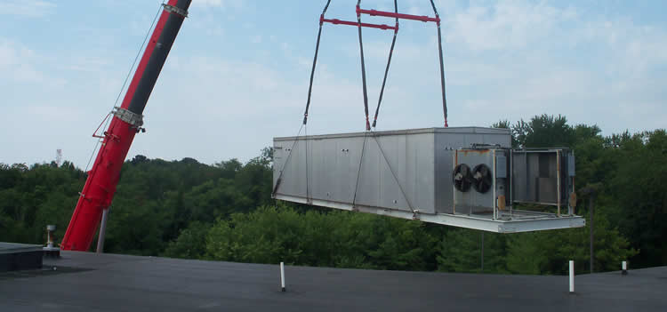A crane lifting commercial refrigeration equipment from a rooftop