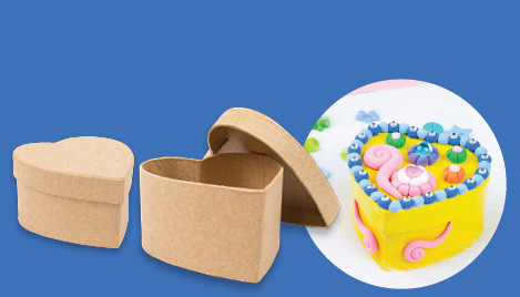 Papier mache heart gift box kit – two plain cardboard heart-shaped boxes with a decorated example covered in colourful clay on a teal background
