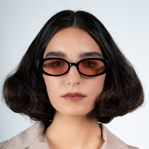 Front view of model wearing sunglasses | Oval sunglasses with pink lenses and black frames | Metal & Acetate | Olivia | Women's sunglasses | Karen Wazen Eyewearv