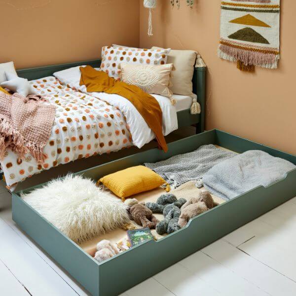 Green daybed with trundle drawer open, showing contents including bedding and toys