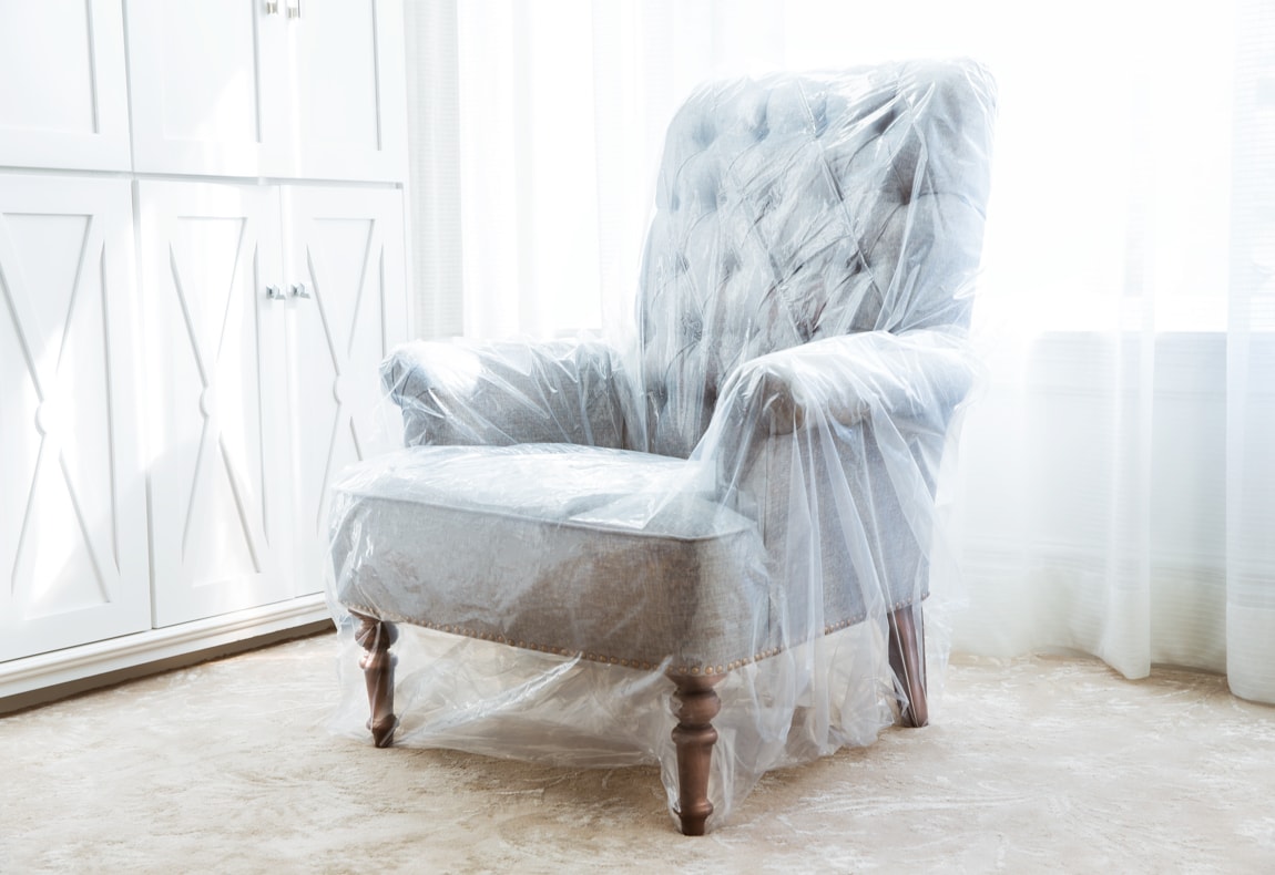 an upholstered chair inside of a storage bag in front of a window