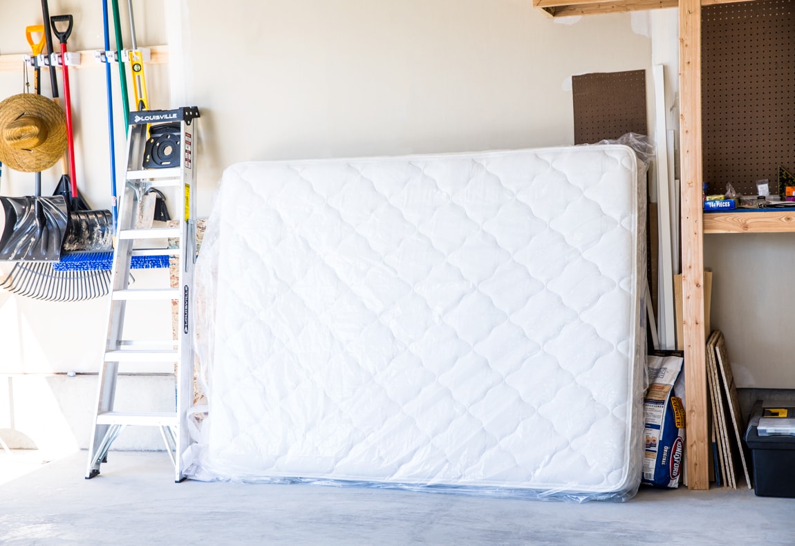a mattress in a storage bag leaning against a garage wall