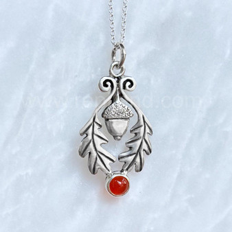 The Flora Gem Pendant features curving oak leaves, a capped acorn and 6mm gemstone. Shown with Cornelian.