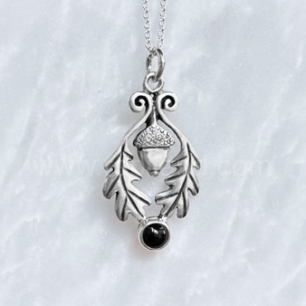 The Flora Gem Pendant features curving oak leaves, a capped acorn and 6mm gemstone. Shown with Onyx.