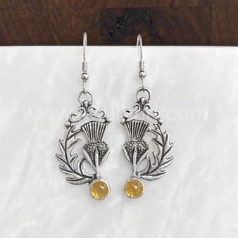 The Cirsium Gem Earrings feature thistle flowers, flanked by a curving leaf on one side, a 6mm gemstone at the bottom and beads and curl accents at the top. Shown with Citrine.