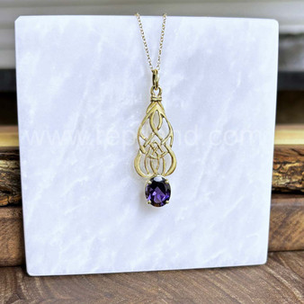 Pendant in 14kt yellow gold with intricate, curving knotwork and a 3.06ct Iolite.