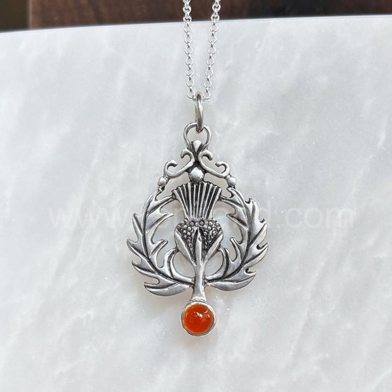 The Lyall Gem Pendant has a central thistle flower, curving side leaves and a 6mm gem at the bottom. Shown with Cornelian.