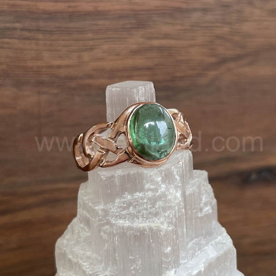 The Elidir Gem Ring features intricate, pierced knotwork with an 8x10mm gemstone. Pictured in rose gold with Green Tourmaline.