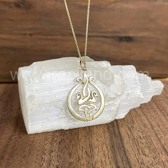 The Cygnet Pendant features 2 entwined baby swans facing outward above a curved trinity knot within a smooth frame. Shown in yellow gold.