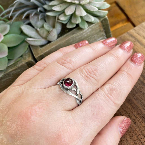 The Mwynen Gem ring features curving pierced knotwork & a 6mm gemstone. Shown with Garnet on size 7 finger.
