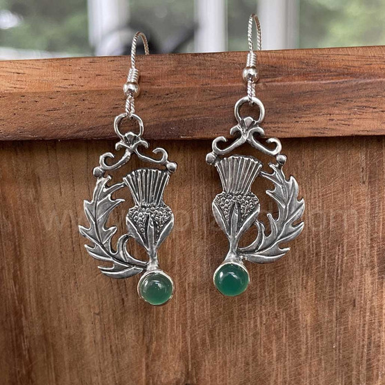 The Cirsium Gem Earrings feature thistle flowers, flanked by a curving leaf on one side, a 6mm gemstone at the bottom and beads and curl accents at the top.