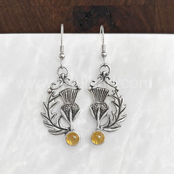 The Cirsium Gem Earrings feature thistle flowers, flanked by a curving leaf on one side, a 6mm gemstone at the bottom and beads and curl accents at the top. Shown with Citrine.