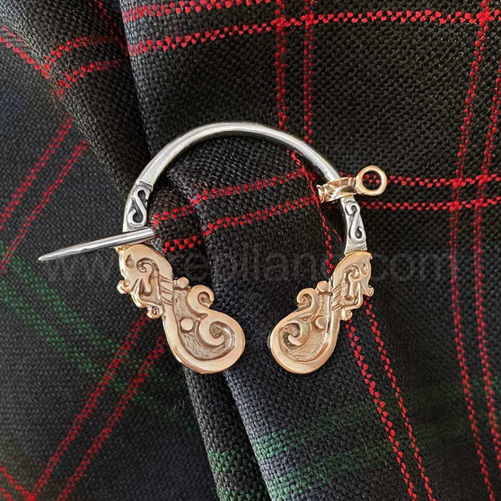 The Môr Draig Penannular has sea dragons on each end. Shown in sterling & 14kt rose gold on Clan Hume tartan.