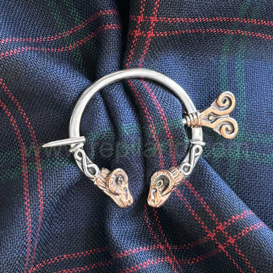 The Dunface Penannular has S curve accents and rams head ends. Shown in sterling & 14kt rose gold on Clan Hume tartan.