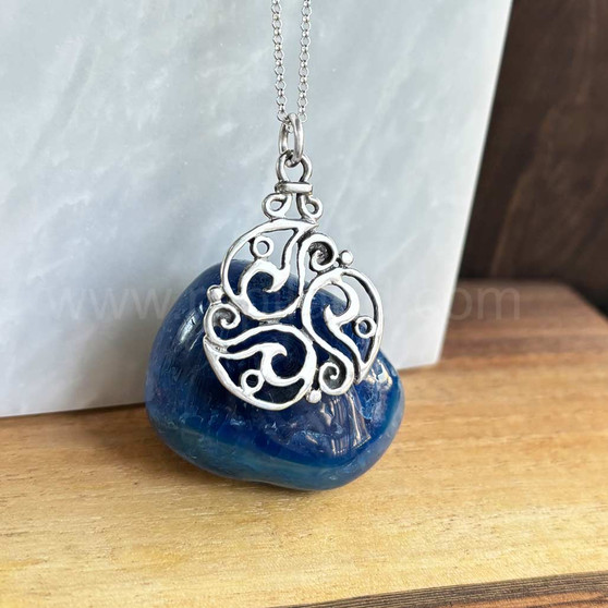 The Inishglora Triskele Pendant features an intricate, openwork circular design based on a traditional triskele motif.