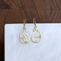 The Avel Earrings feature a stylized wave pattern, shown in 14kt yellow gold.