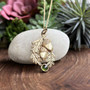 The Coille Gem Pendant features acorns, oak leaves and a 6mm gem. Shown in 14kt yellow gold with a Green Tourmaline.