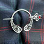 Penannular featuring elongated trinity knots and swirled ends, pin top has 6mm gem. Shown in Garnet on Clan Hume tartan.