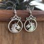 The Dìleab Earrings have a unicorn head in profile within a circle frame.