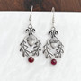 The Flora Gem Earrings feature curving oak leaves,  capped acorns and 6mm gemstones. Shown with Garnets.