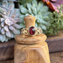 The Elidir Gem Ring features intricate, pierced knotwork with an 8x10mm gemstone. Pictured in yellow gold with Garnet.