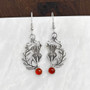 The Cirsium Gem Earrings feature thistle flowers, flanked by a curving leaf on one side, a 6mm gemstone at the bottom and beads and curl accents at the top. Shown with Cornelian.